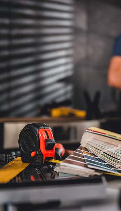 Picture of color swatch with tape measure on the table in the kitchen with couple standing in the background