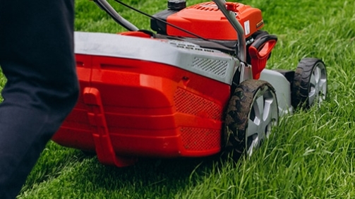 Man cutting grass with lawn mover in the back yard